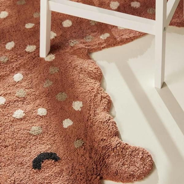 Brown rug with white and beige polka dots on a white floor.