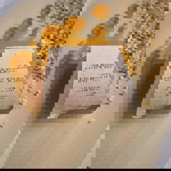 Soap bar labeled 'Ralph's Orchard Honey & Oatmeal' with honey and oats on a wooden surface.