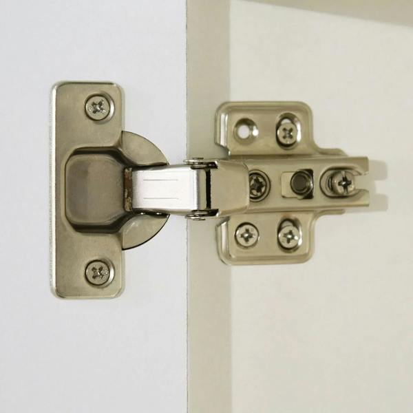 Gold cabinet hinges and latch hardware on a white door panel