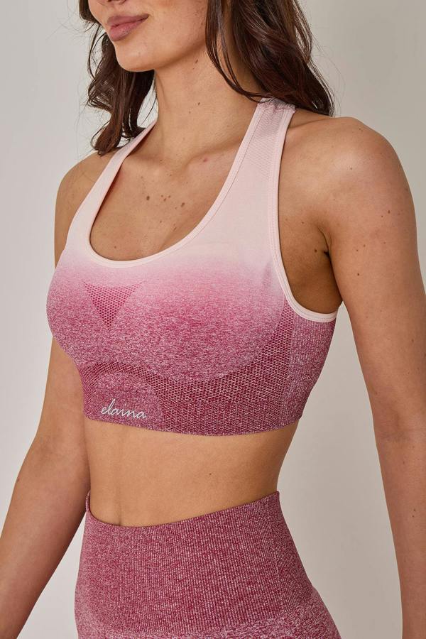 Woman wearing a pink and white sports bra with a matching leggings set on a neutral background