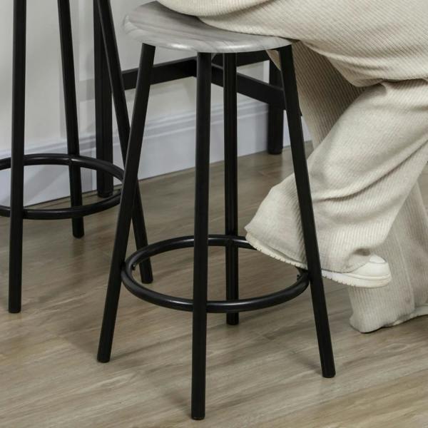 Round grey bar stool with black metal legs and circular footrest, industrial style