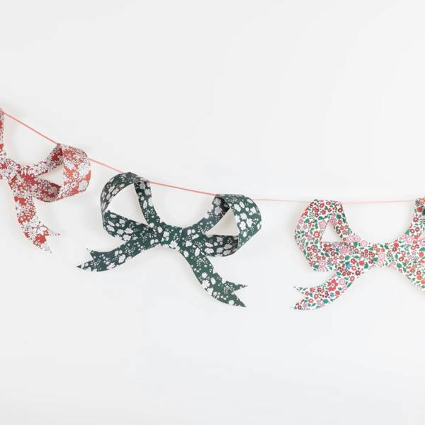 Three 3D paper bow pennants in contrasting red, green, and multicoloured Liberty floral prints hanging against a plain white background.