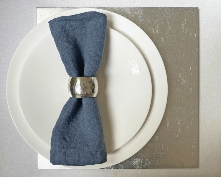 square silver placemat beneath luxury dining plates