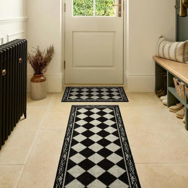 Black and white checkered rugs on a tiled floor with a bench and plant in the background.