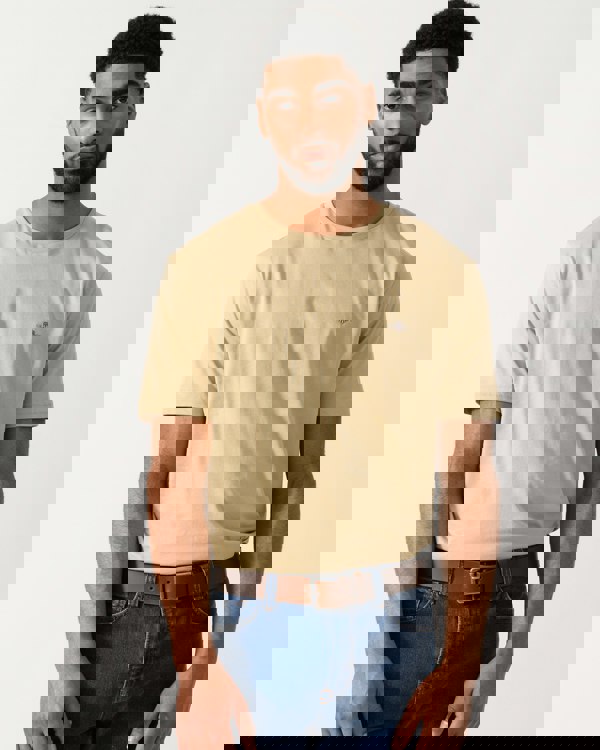 model wearing a GANT Mens Regular Fit Short Sleeve Shield Logo T-Shirt in Oat Beige