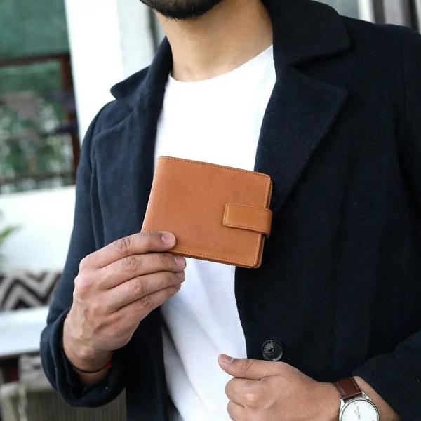 Person holding a cognac leather wallet with a blurred background