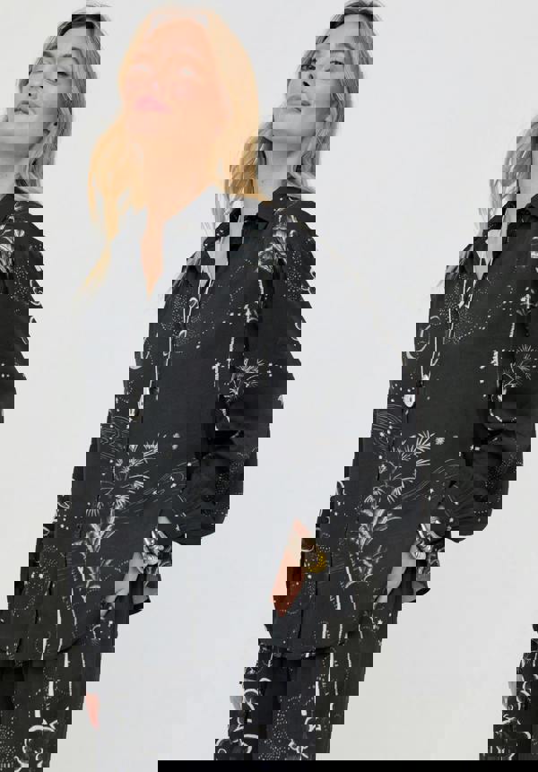 Woman wearing a black patterned shirt and pants on a white background