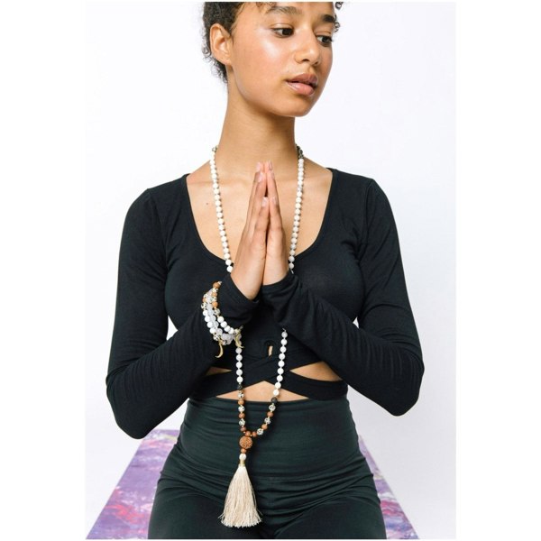 Woman wearing Selene purity mala bracelet and necklace by Kati Kaia while meditating in black outfit