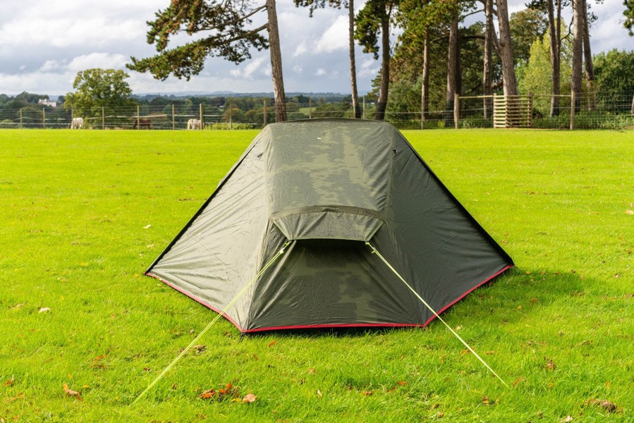 The OLPRO Hawford Lightweight 2 Person Tent (Ripstop) from the end with a treeline in the background pitched in a field.