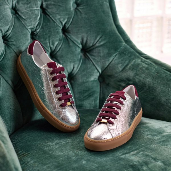 Silver star sneakers with cherry laces on a green cushioned chair