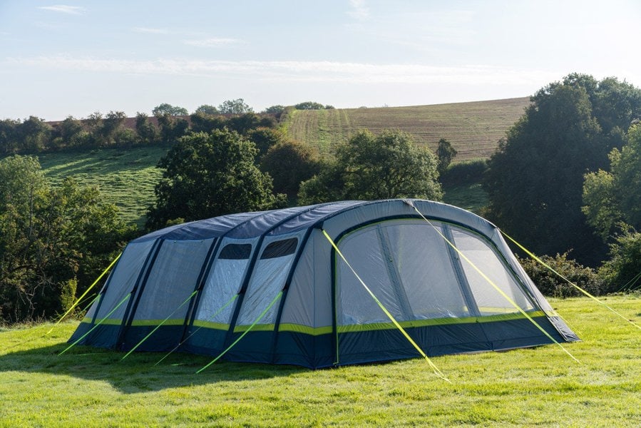 The OLPRO Odyssey  Breeze® Inflatable 8 Berth Tent pitched in a campsite with a treeline in the background.