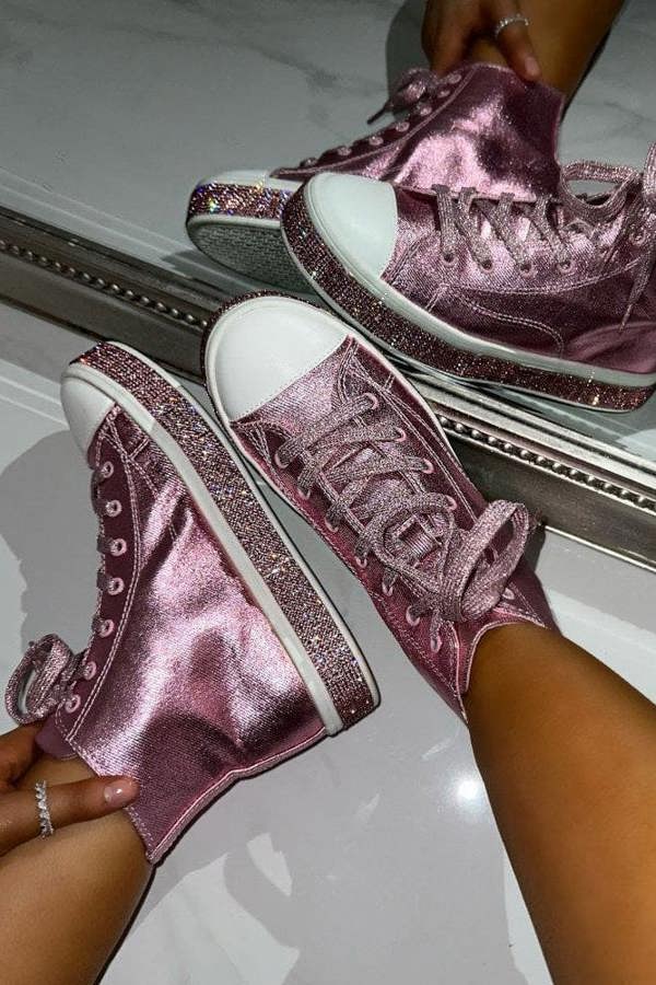 Pink glittery high-top sneakers being worn against a mirror.