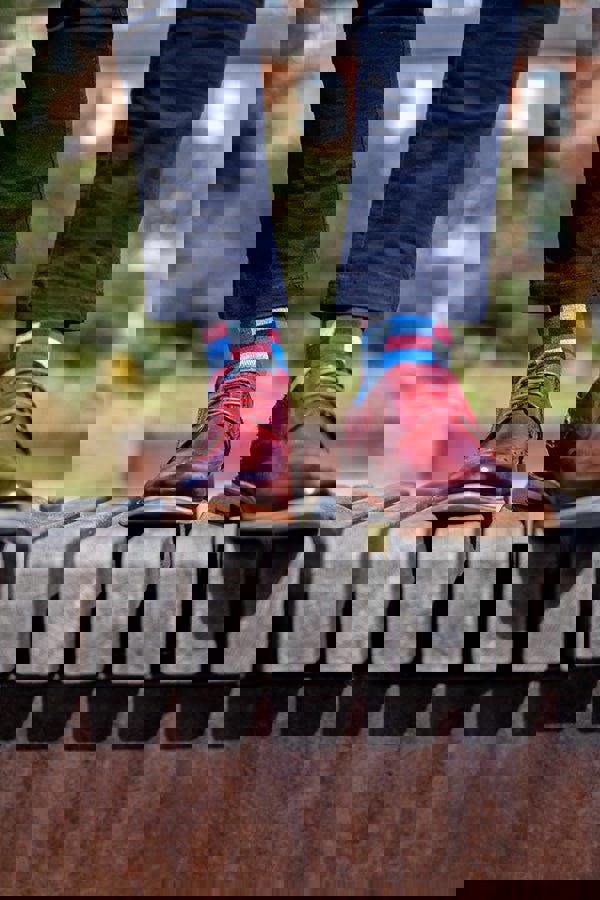 Person wearing red shoes and colorful socks standing on a metal railing with a blurred background