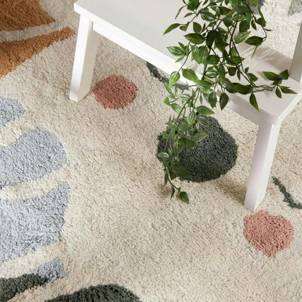 Patterned rug with geometric shapes and a white table with a plant on it