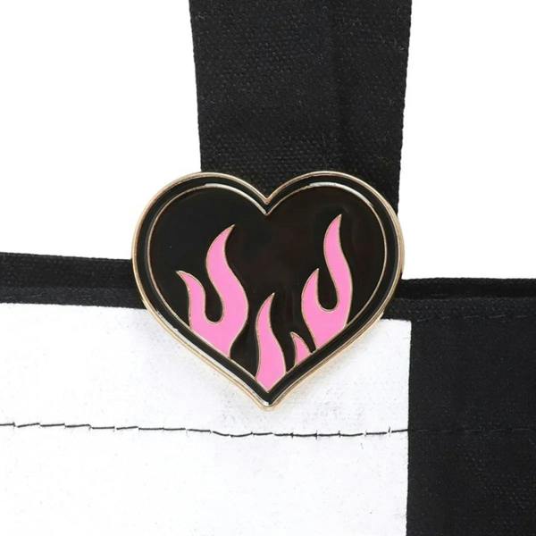 Enamel heart pin badge with pink flames on black and white checkerboard fabric