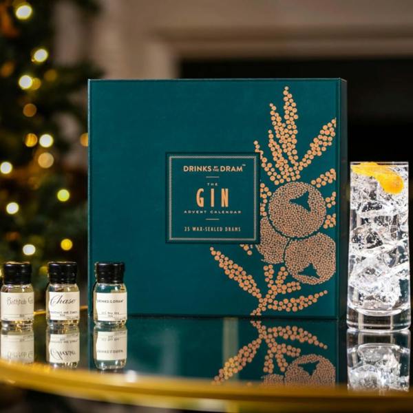 Green and copper Gin Advent Calendar box next to three wax-sealed miniature gin bottles and a G&T glass.