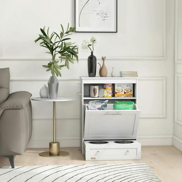 White pet feeder cabinet with open storage shelf and raised bowls beside wall decor.