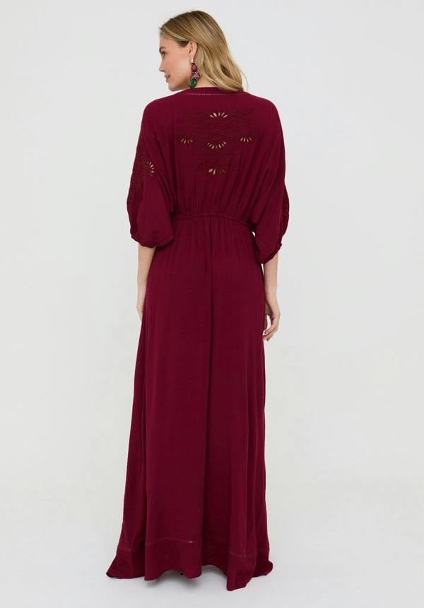 Woman wearing a burgundy dress with floral embroidery on a white background