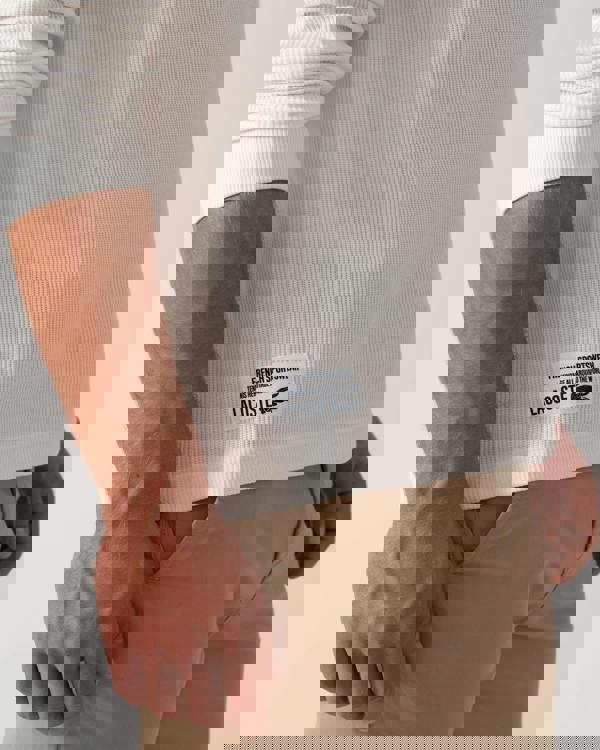 Model wearing Lacoste Boxy Tunisian Neck Knit T-Shirt in Flour 70V - Logo detail