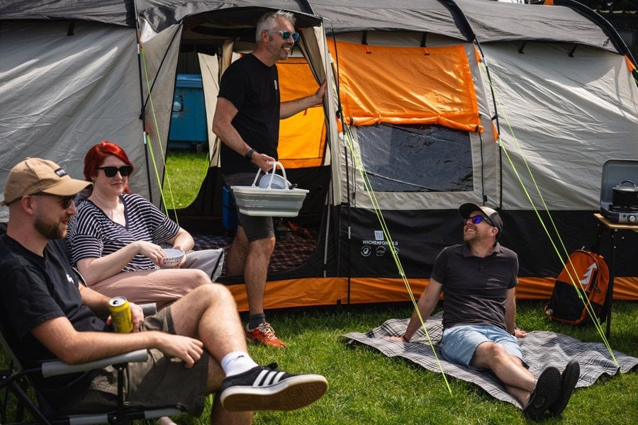 A group of four friends relax outside The Wichenford 8.0, sat on OLPRO camping chairs & a picnic blanket.