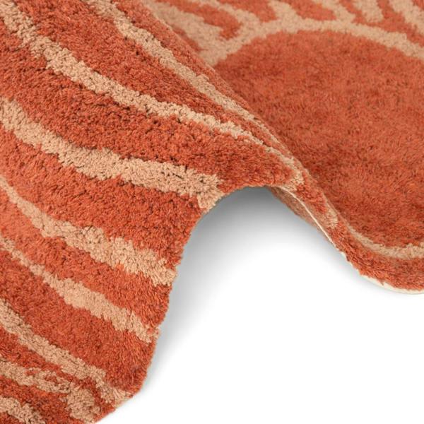 Close-up of a textured orange rug with beige patterns on a white background