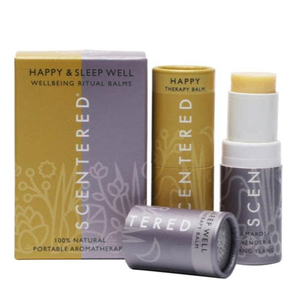 This image showcases Scentered's Wellbeing Ritual Balms for happiness and sleep well. The set includes a "HAPPY THERAPY BALM" and a "SLEEP WELL THERAPY BALM" with ingredients like palmarosa, lavender, and ylang ylang, all presented in 100% natural, portable aromatherapy packaging.