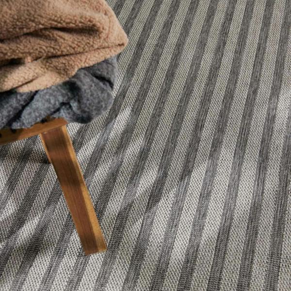 Close-up of a textured gray and white striped carpet with a wooden chair leg visible.