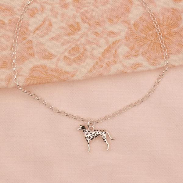 Necklace with a dalmatian dog pendant on a beige fabric background