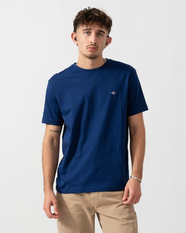 model wearing a GANT Mens Regular Fit Short Sleeve Shield Logo T-Shirt in Rich Navy