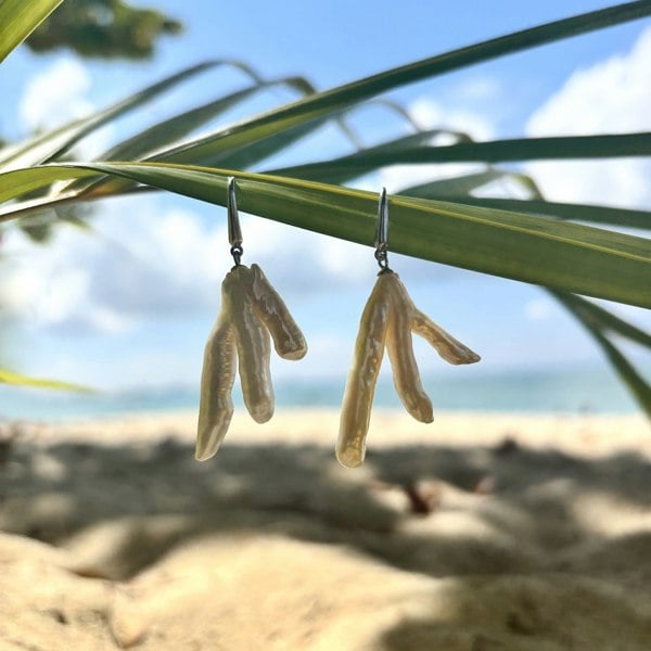 Irregular, luxury pearl earrings by LENAE, handcrafted in silver in London, UK. Shown on a palm leaf.