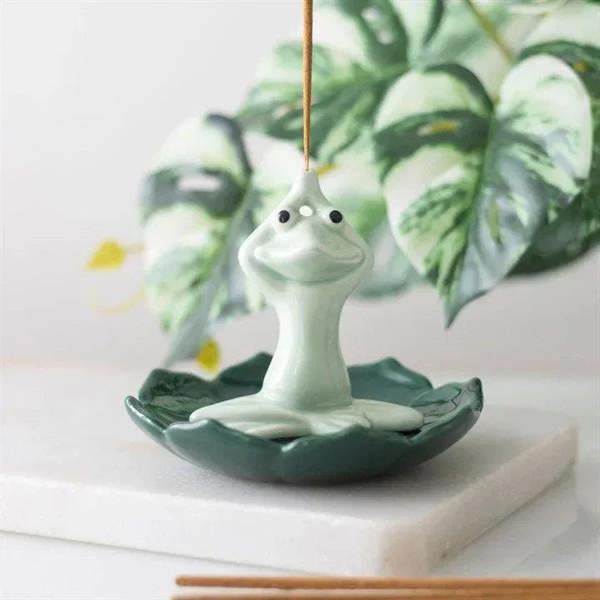 Frog incense stick holder with upright incense stick on green ceramic dish