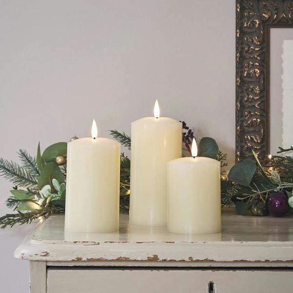 TruGlow ivory rechargeable LED candles on a rustic wooden side table with a cosy living room background.
