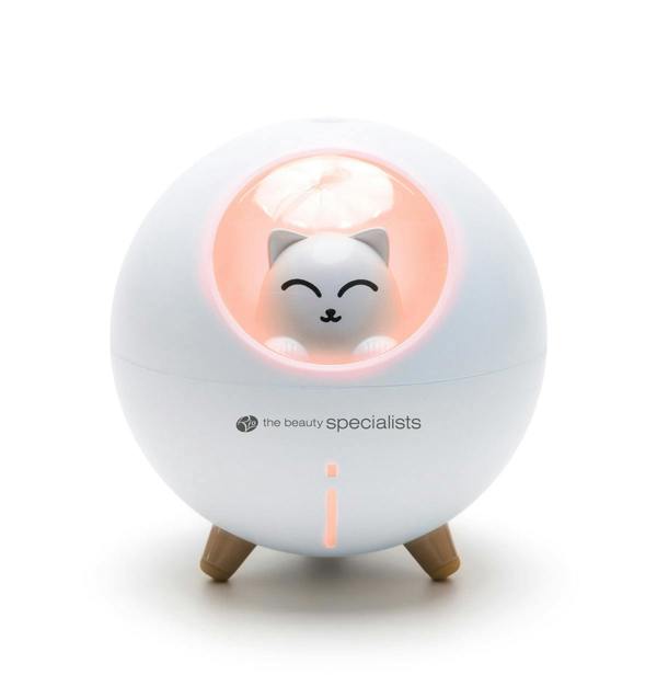 The Rio MIA Cat Childrens Essential Oil Diffuser, Humidifier, and Night Light features a round white design with wooden legs and a small smiling cat inside a pink-lit window, plus “the beauty specialists” below the window.