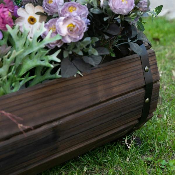 Close-up of dark brown wooden planter box with metal strap corners and pink flower blooms