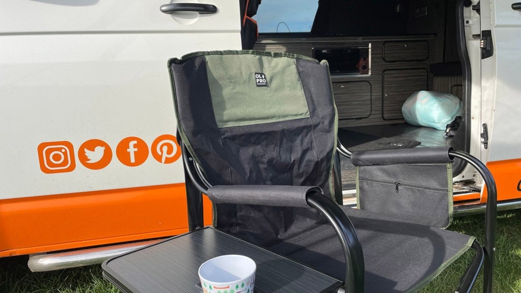 The OLPRO Directors Camping Chair in green and black with the side table up pictured in front of a VW campervan.