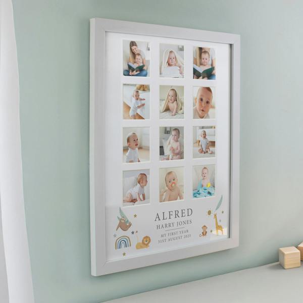 A large white multi photo frame showcasing a 12-picture grid of a baby's first year, featuring custom uppercase text 'ALFRED HARRY JONES' and cute animal illustrations, hanging on a sage green nursery wall.