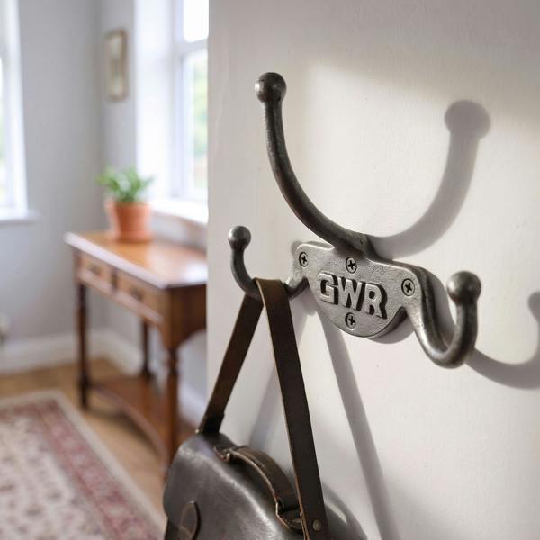 Close-up of GWR Railway Triple Coat Hook on a light-colored wall in a cozy hallway, featuring vintage cast iron finish and three hooks supporting a bag.