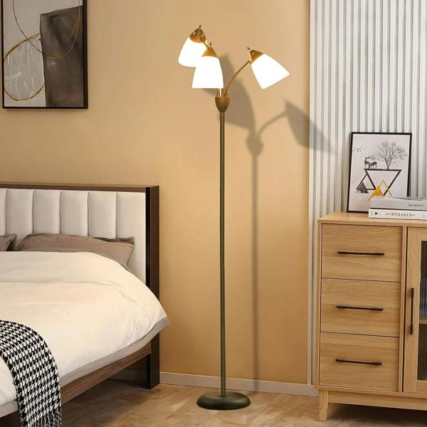 Black floor lamp with three lit adjustable rotating heads and white bell shades in bedroom