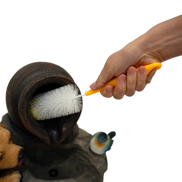 Hand cleaning the Electric Water Feature - Canine Creek with a brush, showcasing the detailed ceramic pot and playful dog design