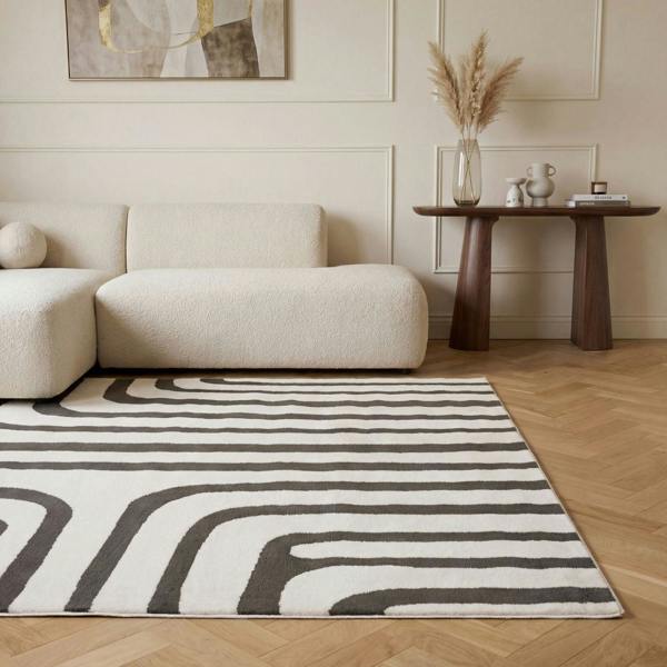 Living room with a beige sofa, abstract rug, and wooden side table.