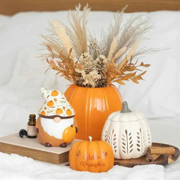 Orange pumpkin-shaped candle with "Hello Pumpkin" text on a wooden display