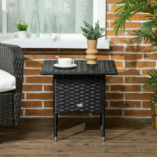 Black woven side table with square top and tapered legs near brick wall