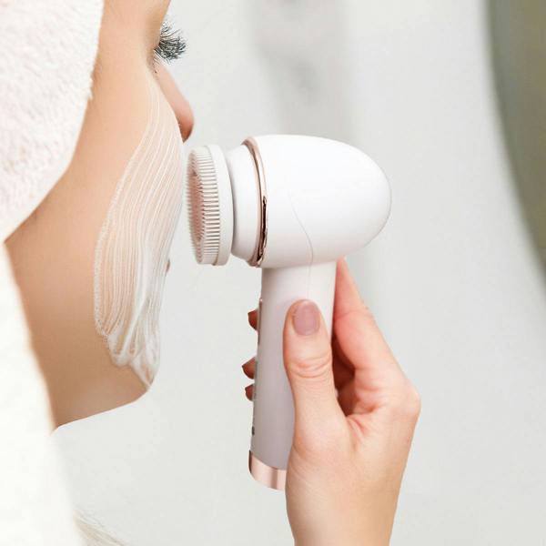 Using the Rio the Beauty Specialists PURE CLEANSE Deep Cleansing & Exfoliating Facial Brush, a person with a white towel on their head exfoliates their foamy cheek as part of a deep skincare routine.