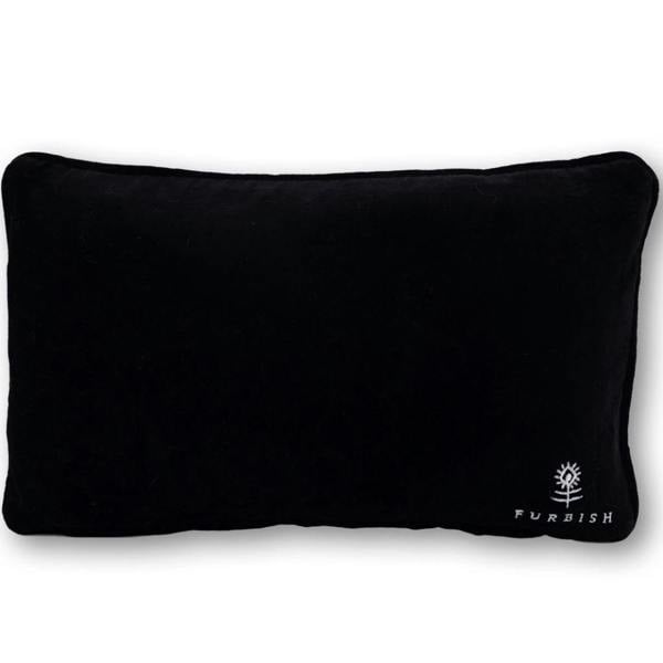 The reverse side of a rectangular statement cushion, showing a smooth black velvet backing with a small white embroidered Furbish Studio logo in the bottom right corner.