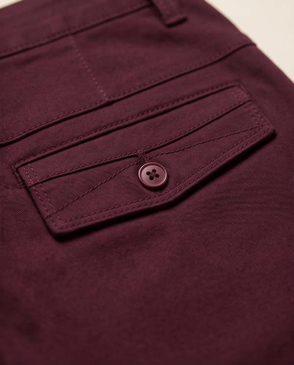 Close-up of a maroon pocket with a button on a matching garment.