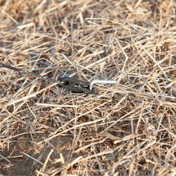 Ground stake peg anchored through the windbreak base on straw