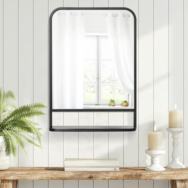 Black wall mirror with storage shelf and rounded top frame.