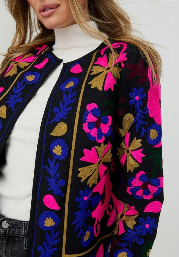 Close-up of a floral embroidered jacket with vibrant colors on a white background