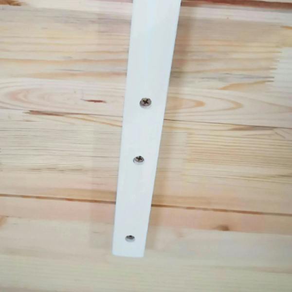 Natural wood tabletop with white painted table leg, close-up of mounting bolts