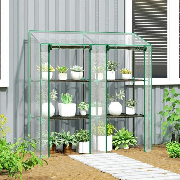 Three-shelf mini greenhouse with clear panels and green frame, plants arranged on wire shelves